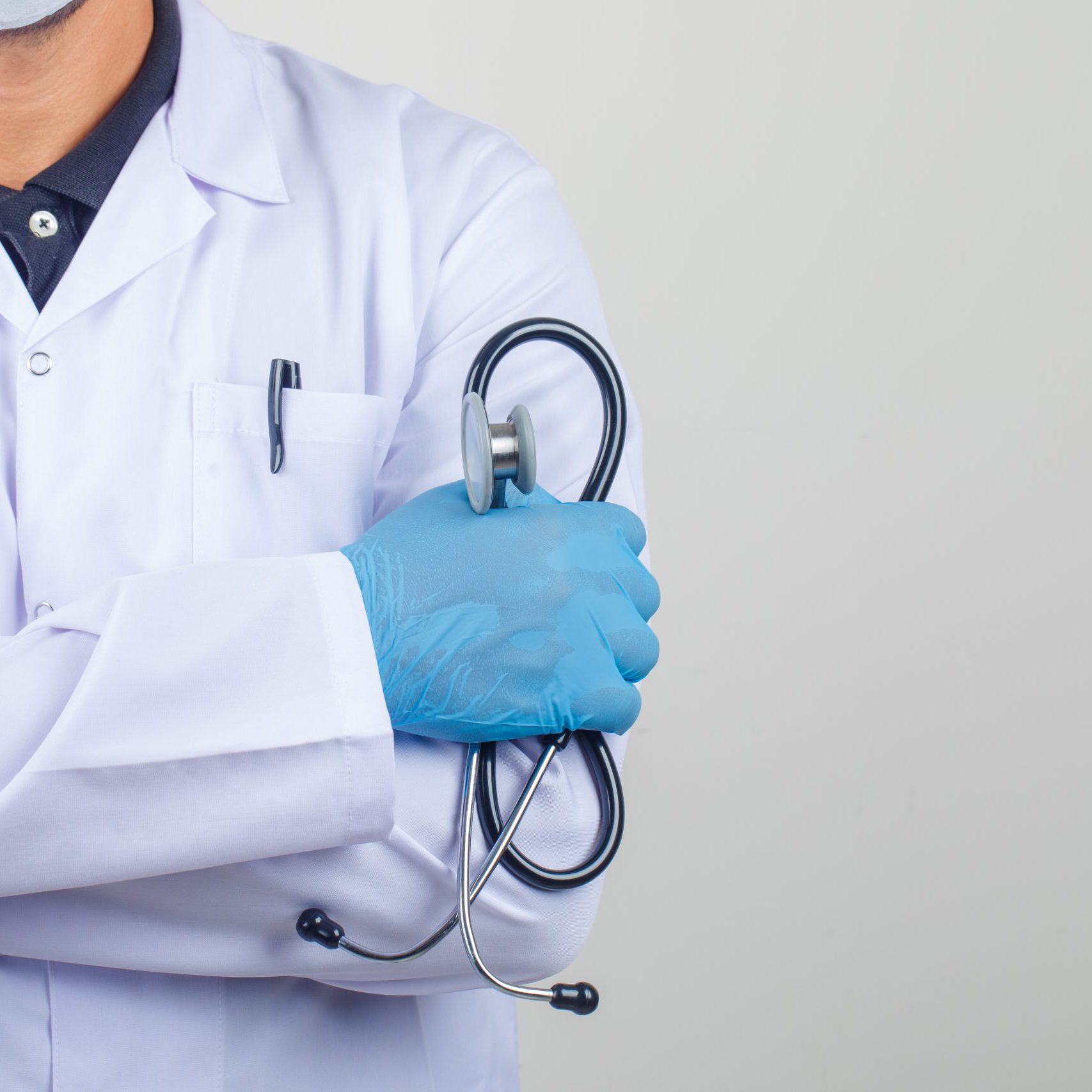 Doctor crossing arms while holding stethoscope in white coat fro Doctor crossing arms while holding stethoscope in white coat front view.
